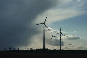 Sturmfront über Windrädern in Sachsen-Anhalt: Die Windturbinenhersteller schreiben Verluste, weil sie (noch) zu wenige Aufträge haben und die Kosten steigen.