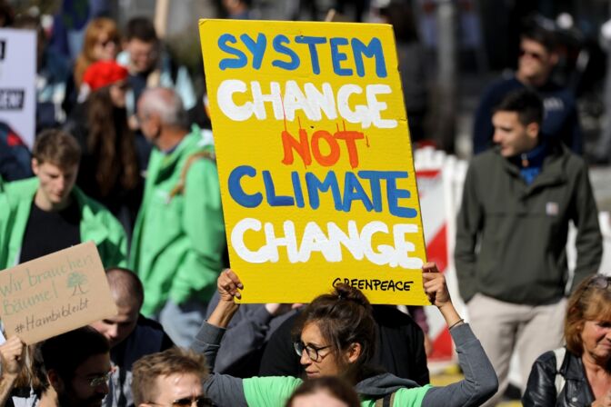 "System Change, not Climate Change" steht auf dem Plakat einer Klimademonstrantin. Klimaschutz und soziale Gerechtigkeit lassen sich durchaus vereinen.