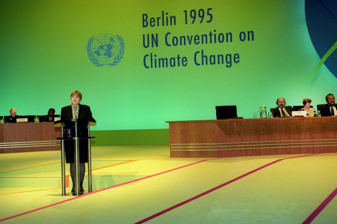 Angela Merkel eröffnet 1995 in Berlin die erste Klimakonferenz. Das Treffen bringt zwar wenig Konkretes, markiert aber dennoch den Auftakt ernsthafter Bemühungen der Weltgemeinschaft um Klimaschutz.