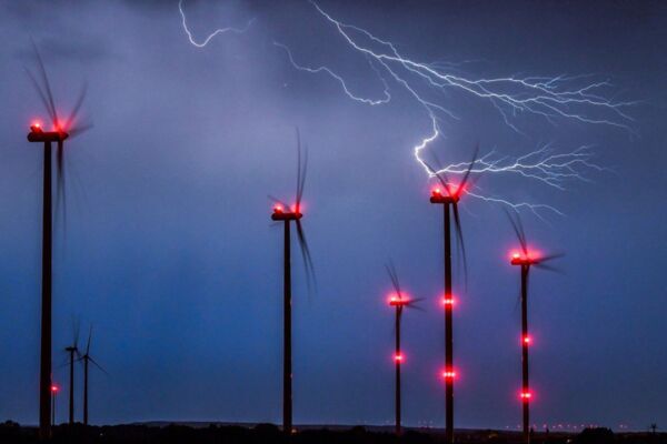 Blitze zucken über einem Windpark durch den Nachthimmel