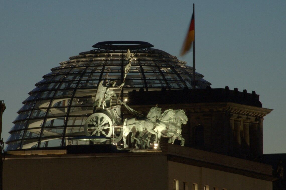 Quadriga auf dem Brandenburger Tor und Reichstagskuppel bei Nacht.