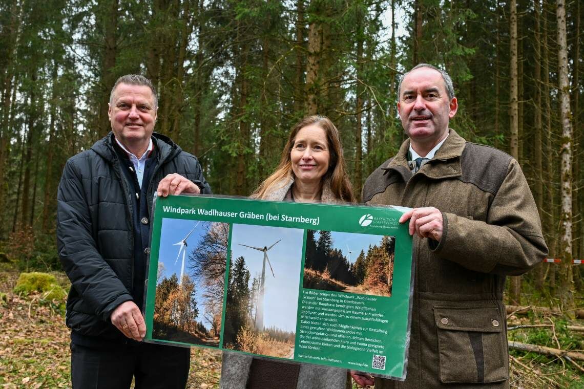 Bayerns Wirtschaftsminister Hubert Aiwanger, Qair-Chefin Heike von der Heyden und Martin Neumeyer von den Bayerischen Staatsforsten zeigen Bilder des geplanten Windparks in Altötting.