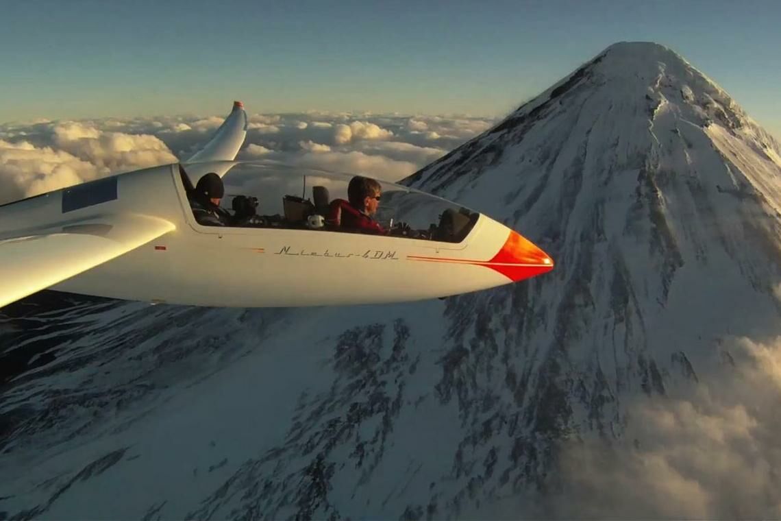 Der sauberste Sport der Welt: Klaus Ohlmann in einem Segelflugzeug vor imposantem Bergpanorama.