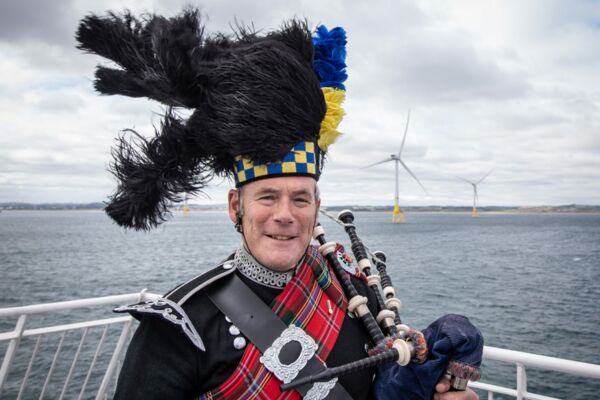Schottland rückt zunehmend in den Fokus der Offshore-Windenergie. Das Foto zeigt einen Dudelsackspieler vor einem Windenergietestfeld bei Aberdeen.
