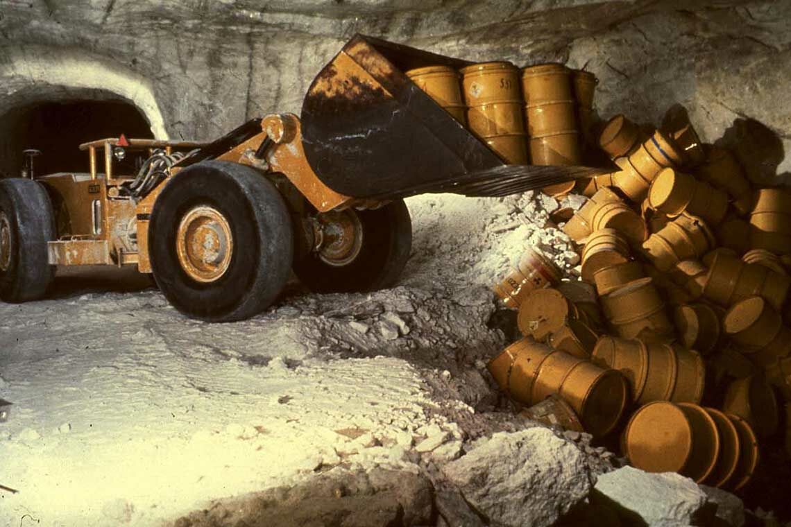 Atommülfässer im Versuchsendlager Asse werden von einem Bagger auf einen Haufen gekippt.