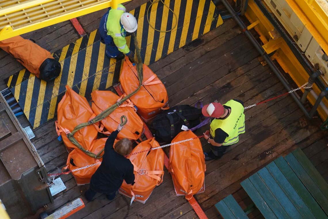 Wenn die orangenen Seesäcke per Kran auf eins der Zubringerschiffe verladen werden sollen, fasst auch Christel Siebens (links) mit an.