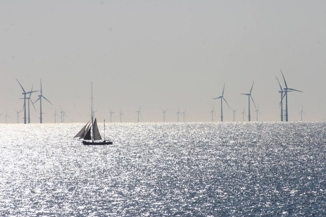 Ein Segelboot fährt durch einen Offshore-Windpark in den Niederlanden.