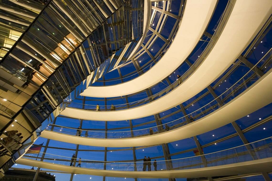Im Inneren der Kuppel des Berliner Reichstags: Bei Nacht hebt sich der Aufgang in golden vom dunklen Himmel ab.