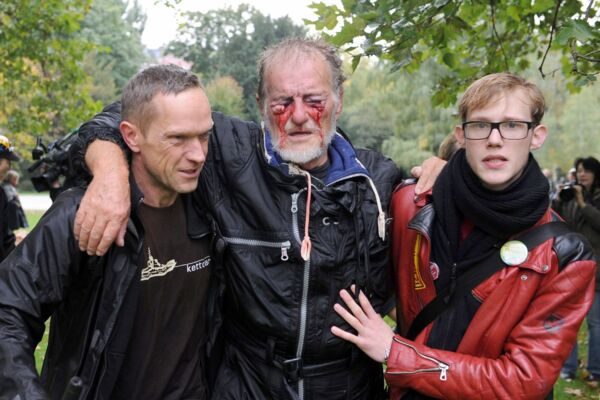 Stuttgart 21: Ein beim Polizeieinsatz im Schlossgarten am Auge verletzter Mann wird von zwei Männern gestützt.