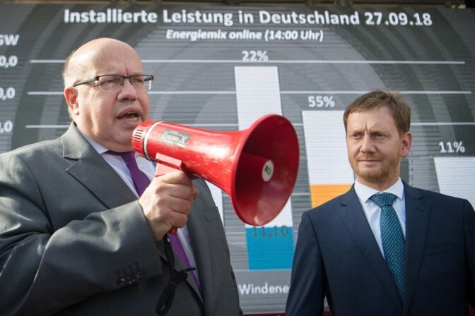 Bundeswirtschaftsminister Peter Altmaier (links) spricht mit einem Megafon über die Energiewende.