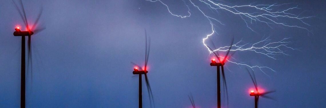 Blitze zucken über einem Windpark durch den Nachthimmel