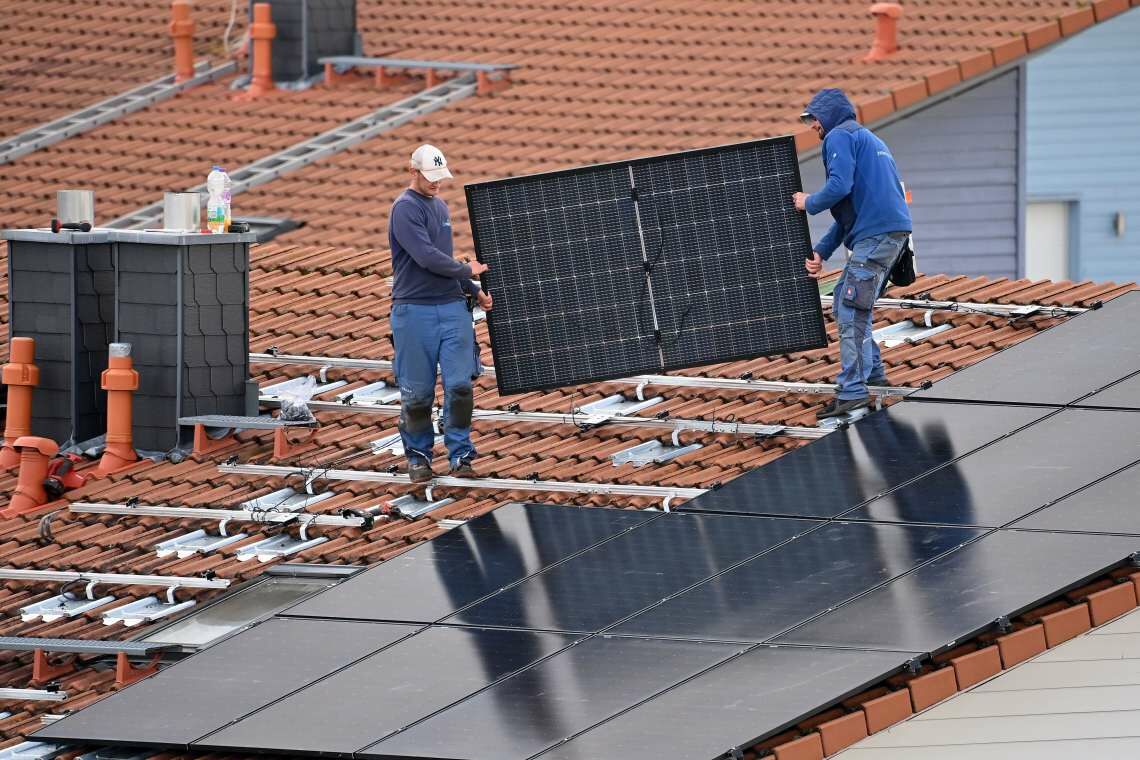 Der Absatz sauberer Technologien boomt weltweit. Hier errichten zwei Arbeiter eine Fotovoltaik-Anlage auf einem Hausdach in Deutschland.