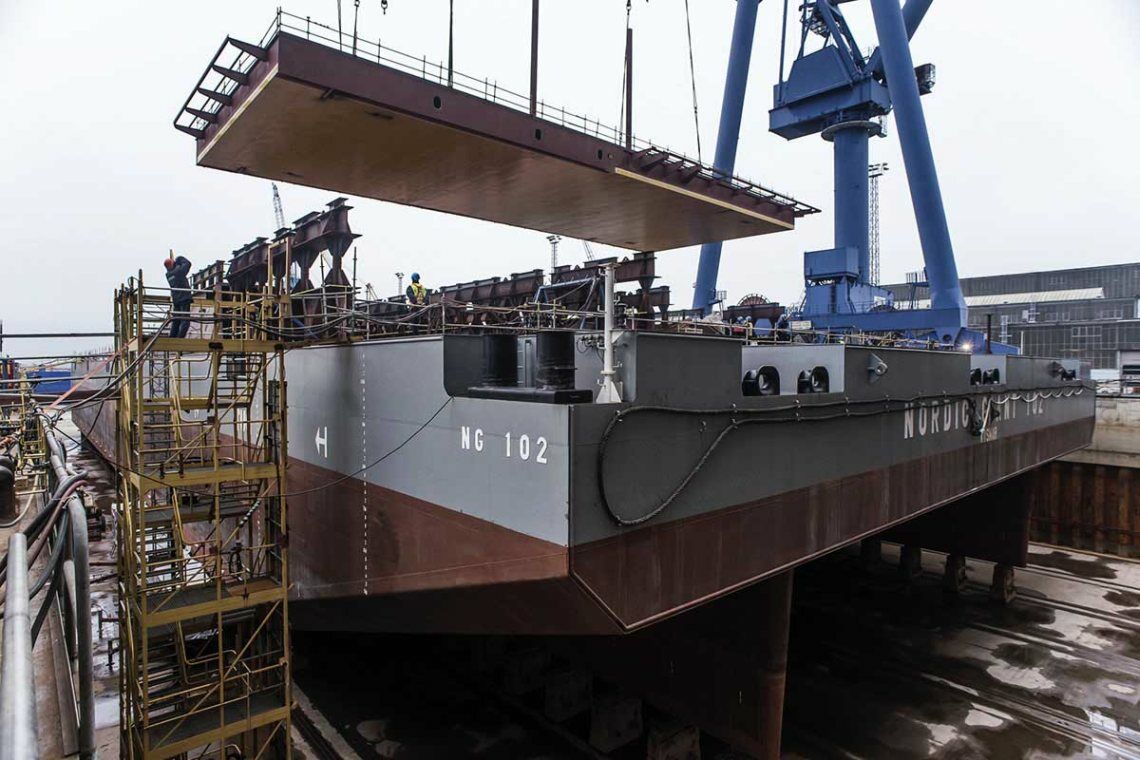 Bau der Konverterstation Dolwin gamma bei Nordic Yards in Warnemünde: Ein Kran hebt eine fast 200 Tonnen schwere Rumpfsektion auf eine Barge.