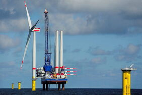 Ein Errichterschiff setzt ein Offshore-Windrad auf ein Transition Piece.