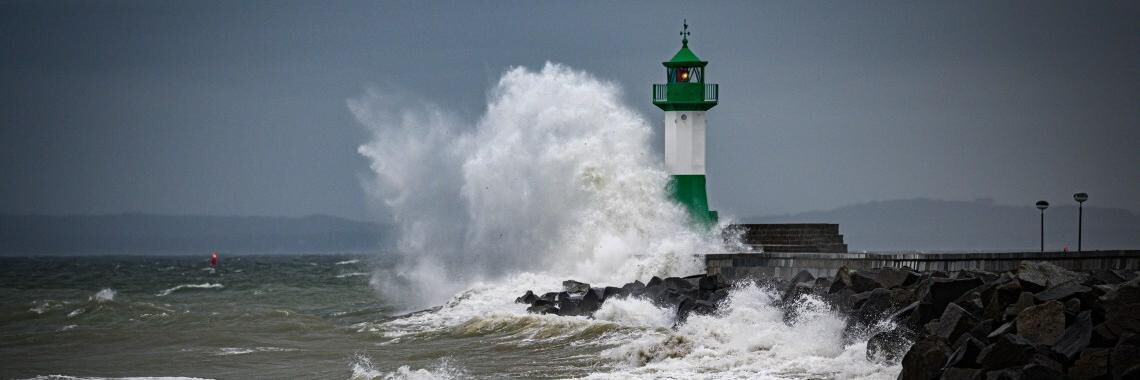Sassnitz: Hohe Wellen brechen an der Hafenmauer beim Leuchtturm im Sassnitzer Hafen auf Rügen.