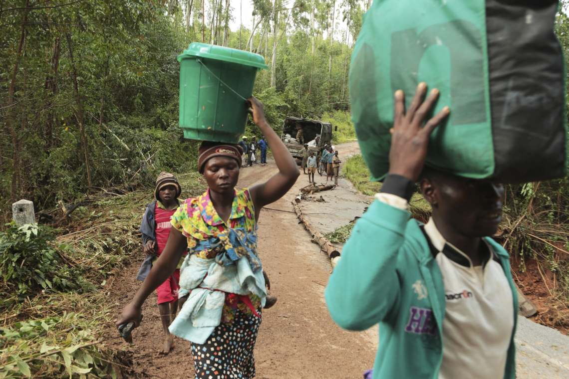 Eine Familie in Simbabwe trägt ihre Habseligkeiten über eine von einem Zyklon zerstörte Straße.