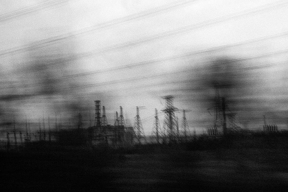 Schemenhaft sind Strommasten und im Hintergrund das Atomkraftwerk Tschernobyl zu sehen. Foto: Arthur Bondar.