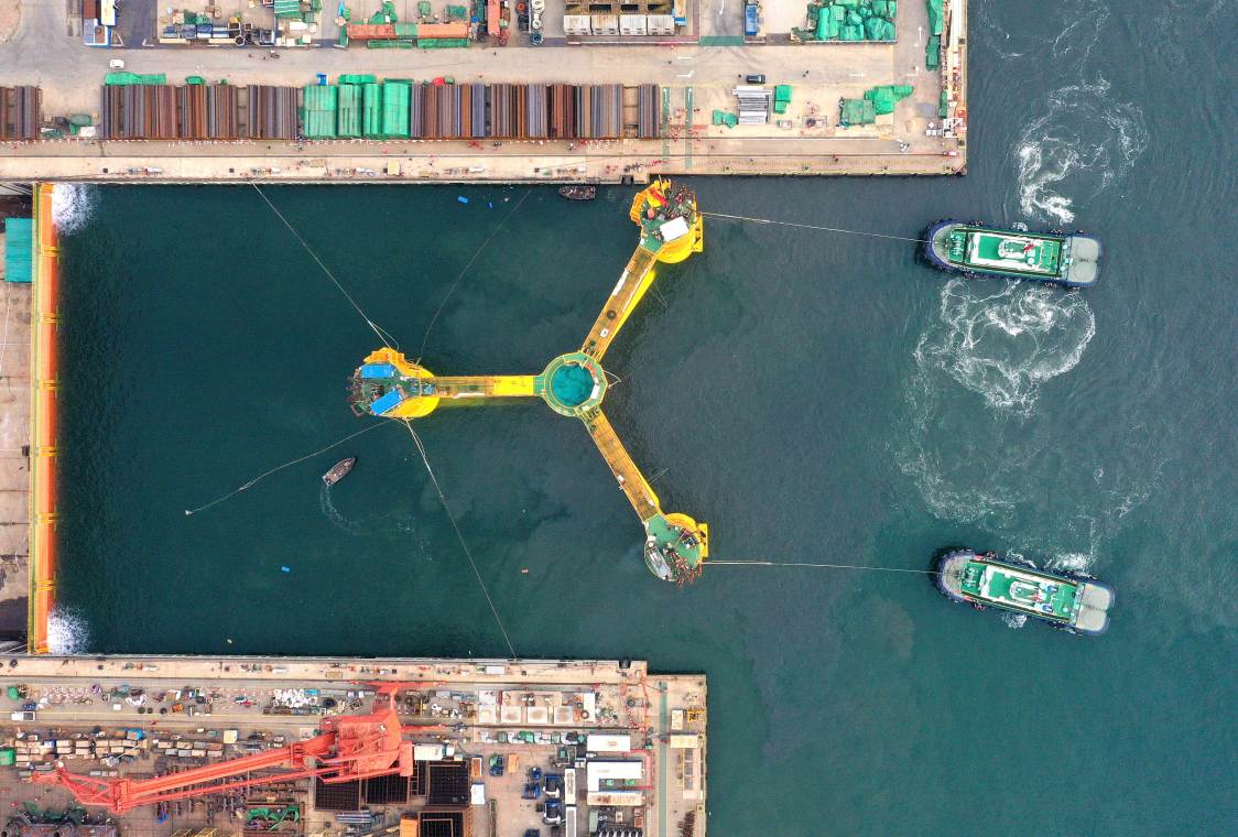Schwimmende Offshore-Windräder in China: Schleppschiffe ziehen das Fundament einer Floating-Wind-Turbine aus dem Hafen.