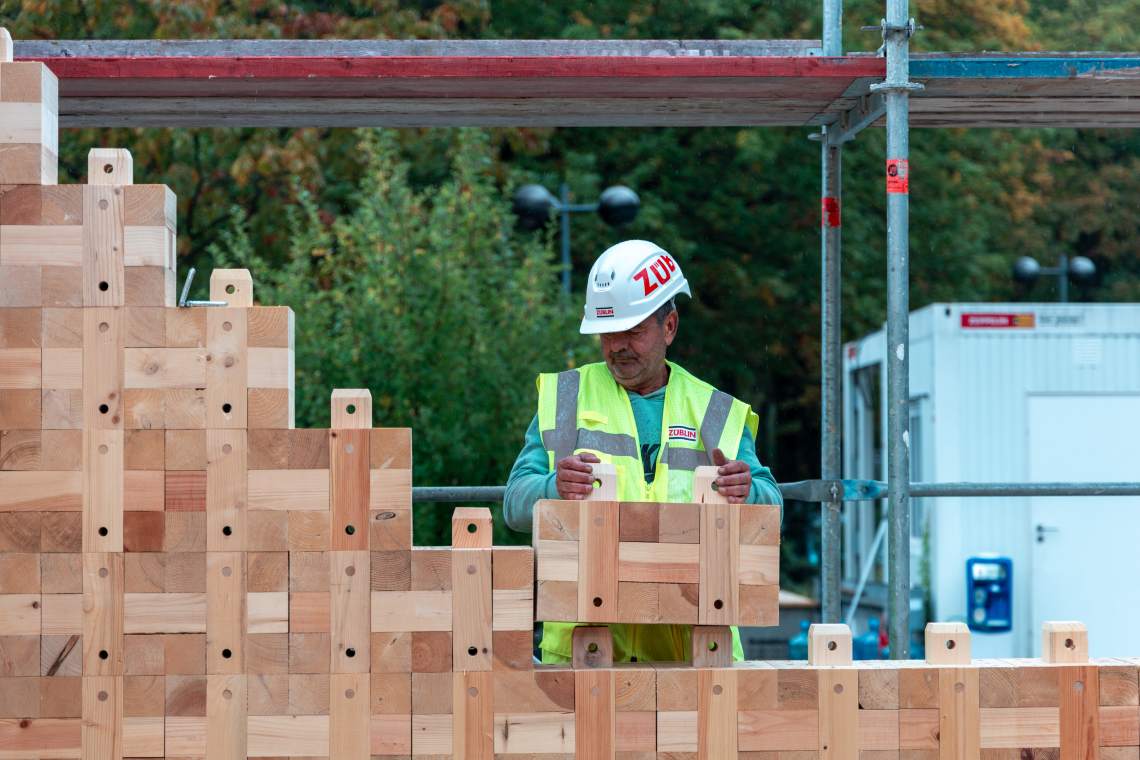 Ein Bauarbeiter setzt ein Haus aus Triqbriq-Bausteinen zusammen. Foto: Triqbriq